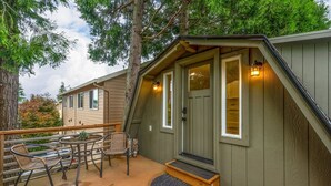 A small cabin with a porch, a table with chairs, and a door with a light above it.