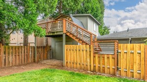 A backyard with a wooden deck, a covered play area, and a fenced yard.