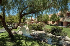 Escape to a serene oasis with a naturalistic water feature, manicured lawns, and lush greenery.