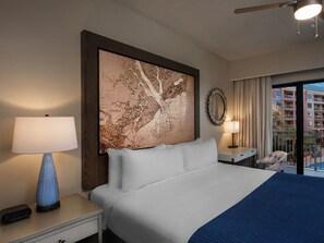 Relax in a spacious room with a large bed, nightstand, and wall-mounted map artwork, offering a view of the outside balcony.