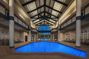 Relax by the pool surrounded by lounge chairs and large windows offering a view of the outdoors.