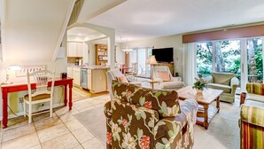 A spacious living area with a kitchen in the background, a dining table with chairs, and a sofa with floral upholstery.