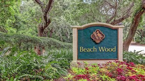 A sign with the text "Beach Wood" surrounded by lush greenery.