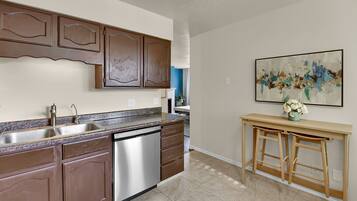 A kitchen with brown cabinets, a stainless steel dishwasher, and a granite countertop.
