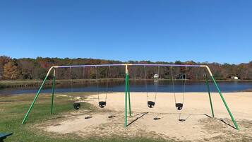 Relax by the serene lake with a family-friendly swing set in a peaceful outdoor setting.