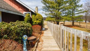 A wooden pathway leading to a red building with a window, surrounded by greenery and trees. - Lakefront Cottage w Fireplace, Private Lake Access, Dock, Big Yard (Albrightsville)