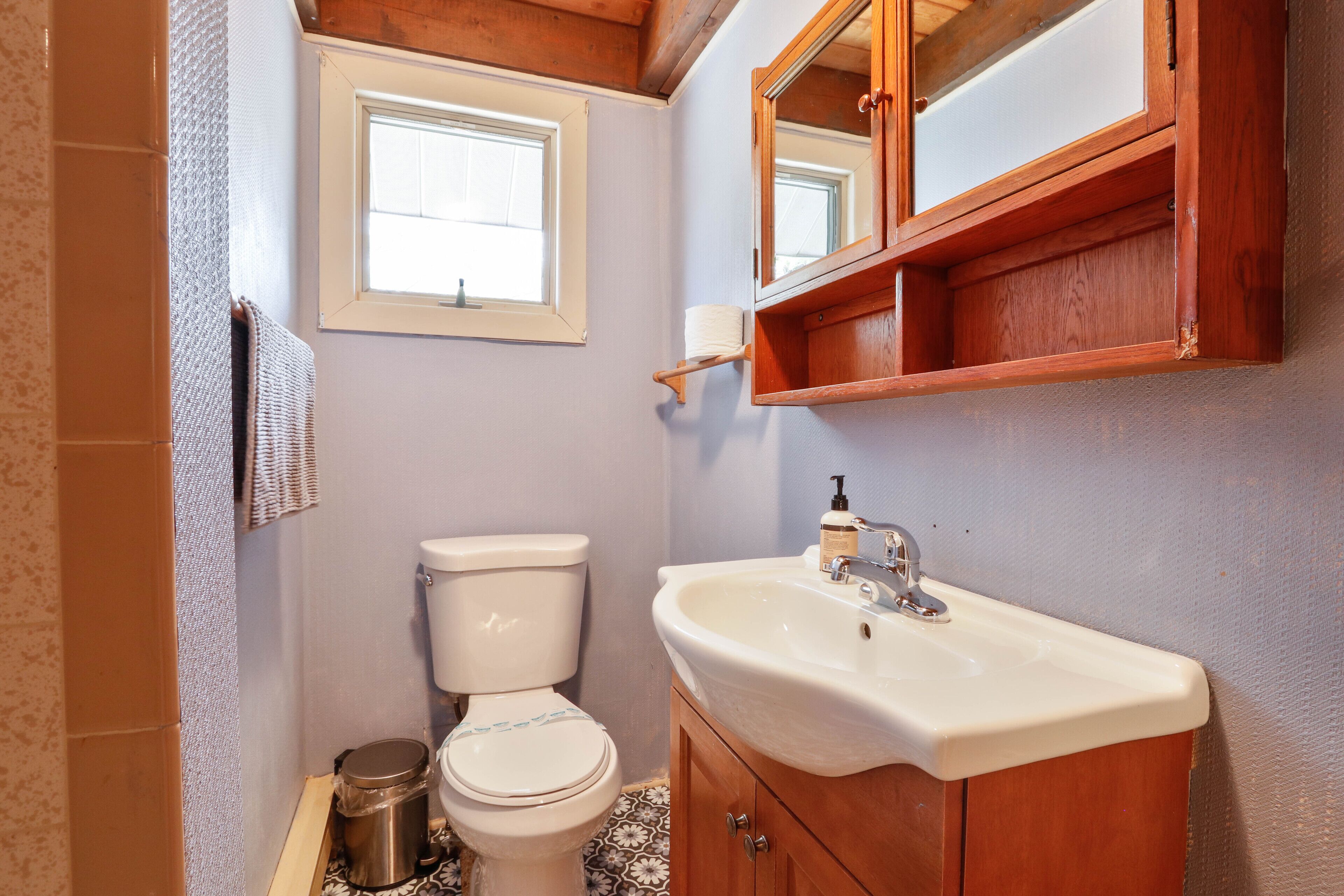 A bathroom with a toilet, sink, and wooden cabinet.
