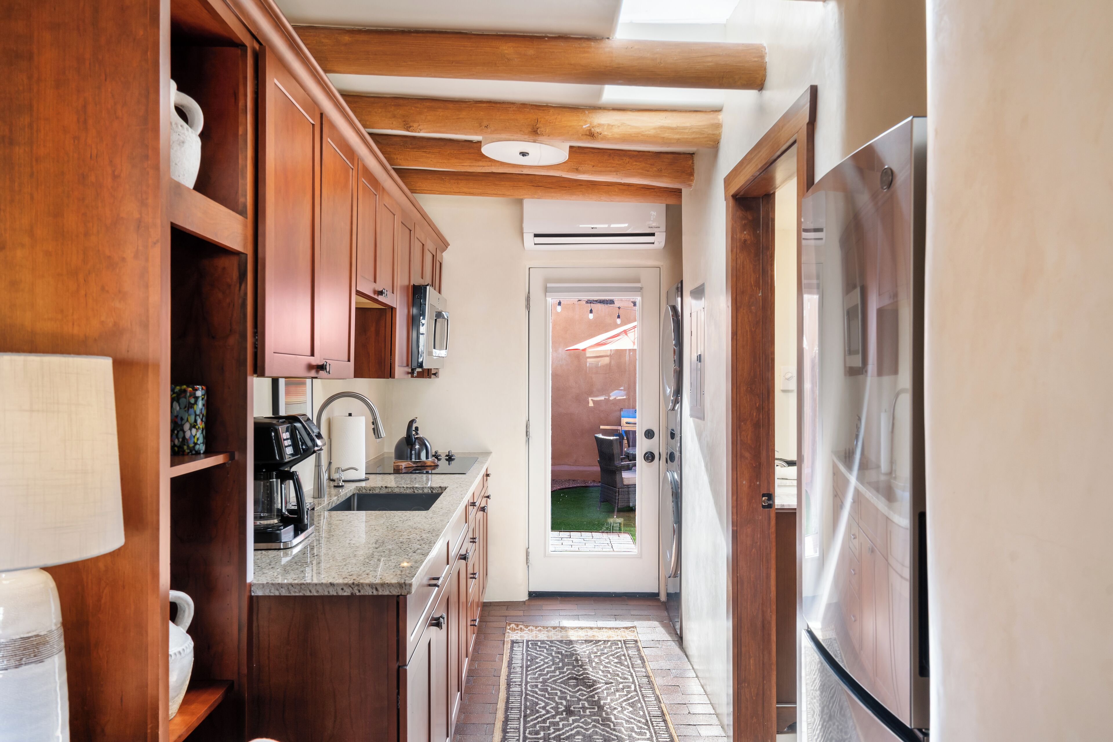 Eine schmale Küche mit Holzausbau, einer eingebauten Mikrowelle und einem Kühlschrank.