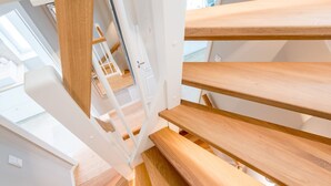 A modern staircase with wooden steps and white railings, leading to an upper floor. - Leev Marie, Germany (Sylt)