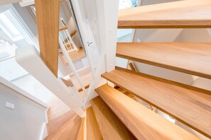 A modern staircase with wooden steps and white railings, leading to an upper floor. - Leev Marie, Germany (Sylt)