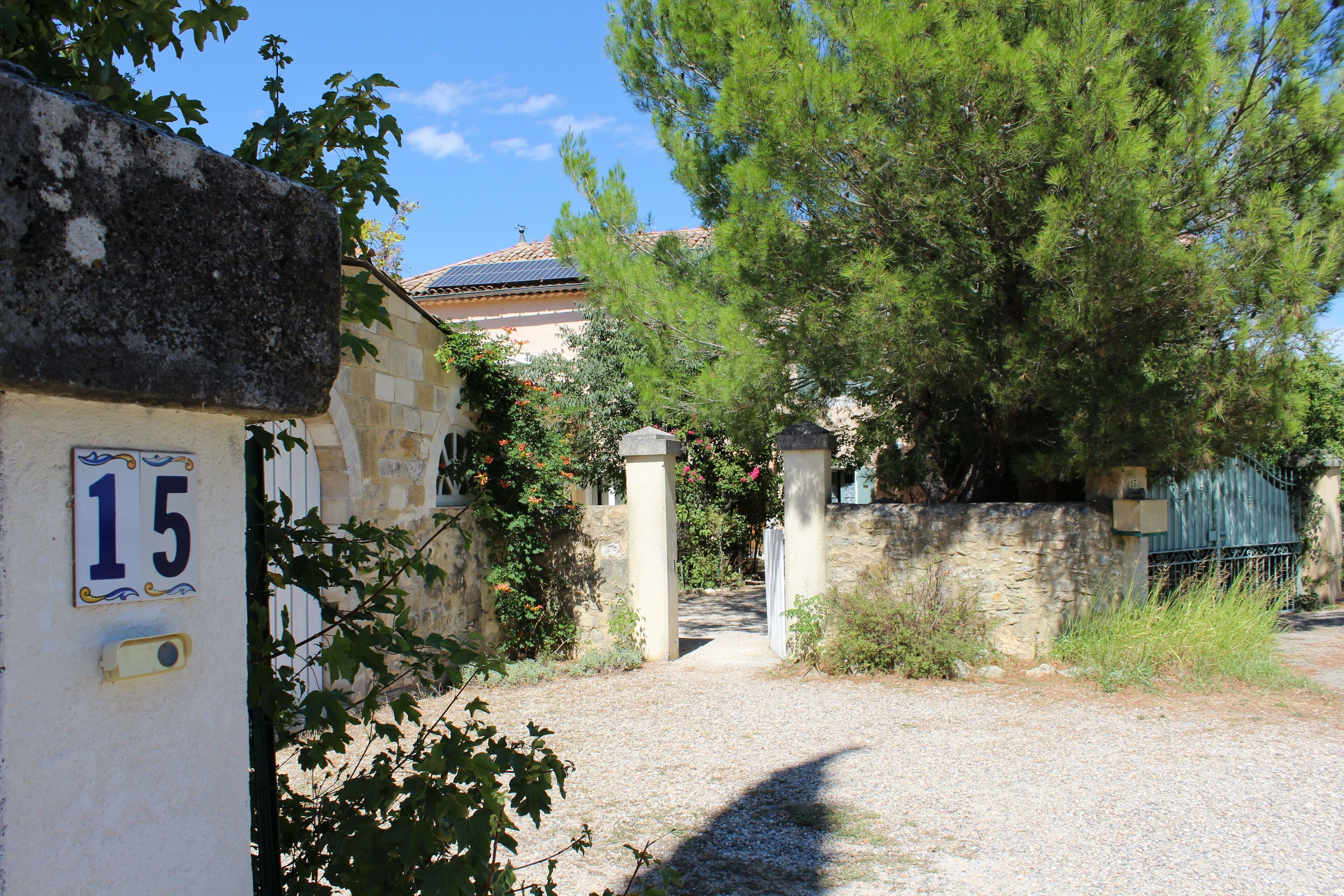 A stone building with a number '15' sign, a gravel path, and a tree in the foreground.