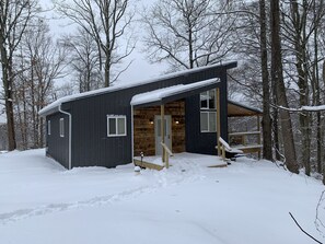 Une cabane avec un intérieur en bois, une véranda et une façade recouverte de neige.