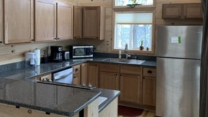 A kitchen with wooden cabinets, a stainless steel refrigerator, a microwave, and a coffee maker.