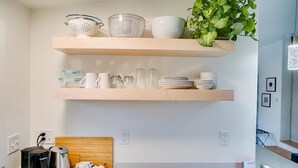 A kitchen with two wooden shelves holding kitchenware, a coffee maker, and a kettle. - #HabitueHomes - Green Spot Studio- Dog Friendly! (Boise)