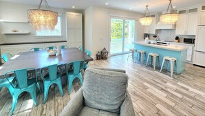 A spacious kitchen with white cabinets, a central island with stools, and pendant lighting.