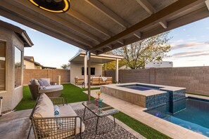 A covered outdoor area with a hot tub, seating, and a small pool.