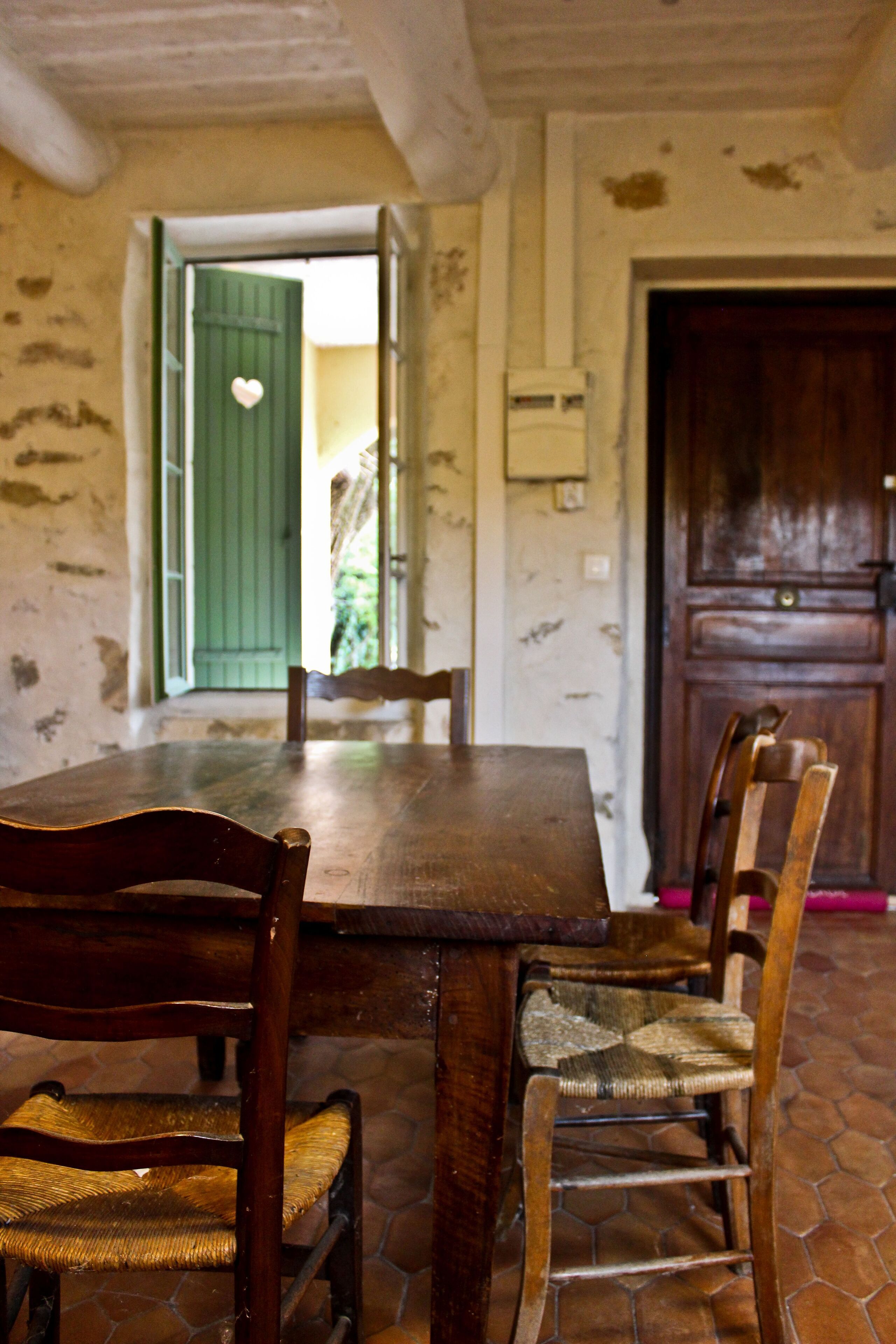 Un coin repas rustique avec une table et des chaises en bois, une porte verte et un buffet en bois.