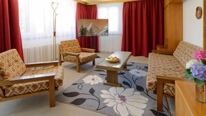 Ein Wohnzimmer mit einer Couch, zwei Sesseln, einem Couchtisch und einem Gemälde an der Wand.