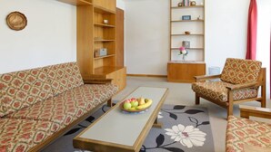 Ein Wohnzimmer mit einer Couch, einem Sessel, einem Couchtisch und einem Bücherregal.