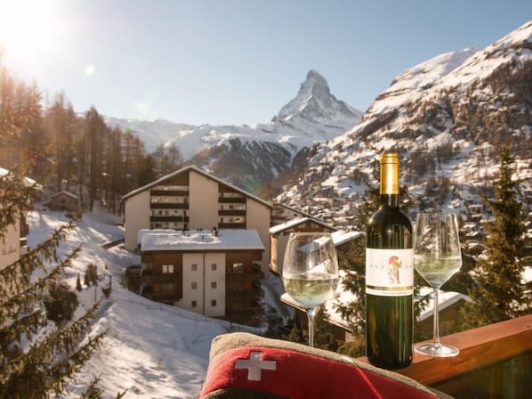 A mountain view with a chalet, a bottle of wine, and two glasses on a balcony. - Hubertus by Interhome (Zermatt)