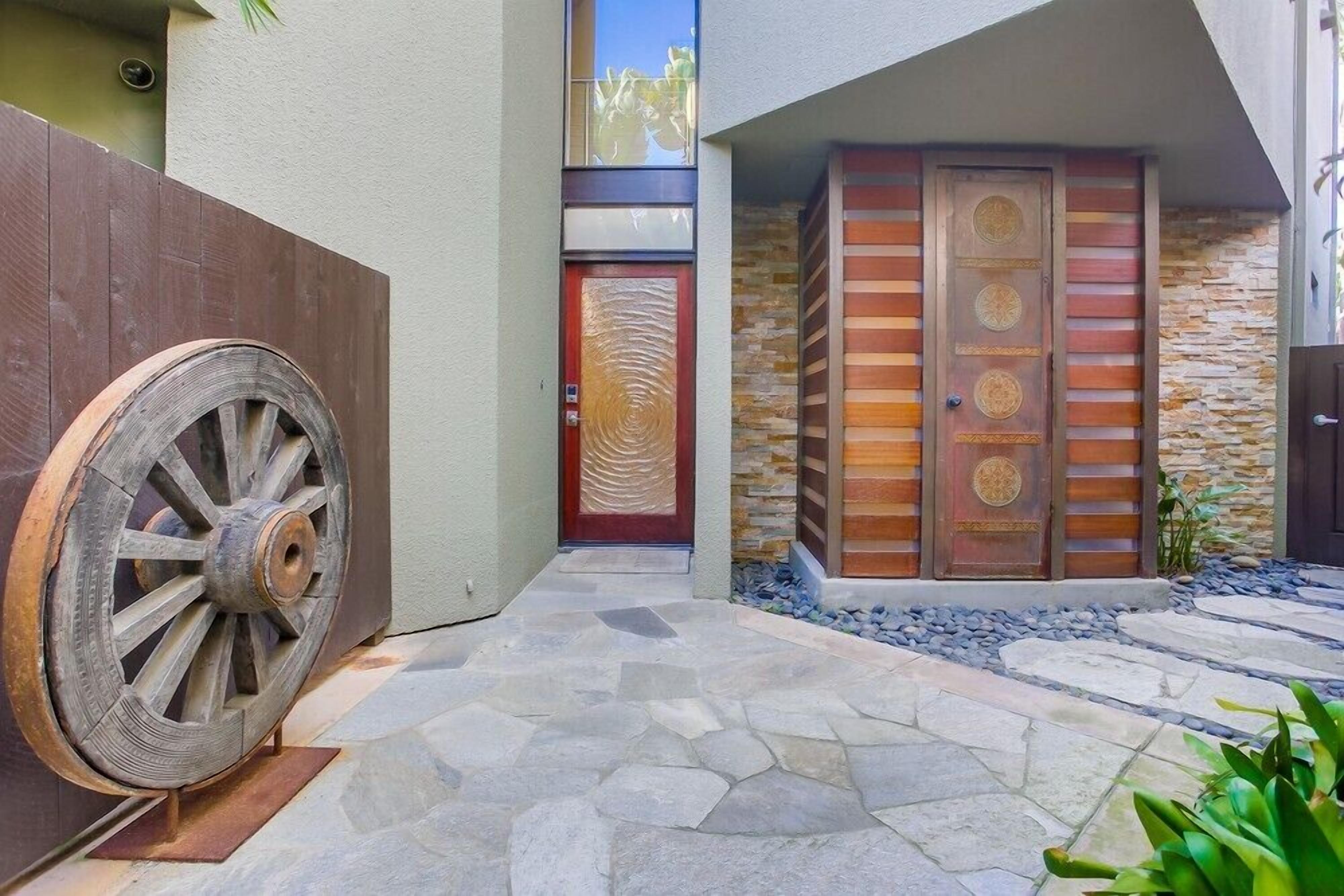 Un edificio moderno con un camino de piedra que conduce a una puerta de madera con diseño circular.