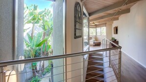 A staircase with a metal railing leading to a room with a large window overlooking a garden.