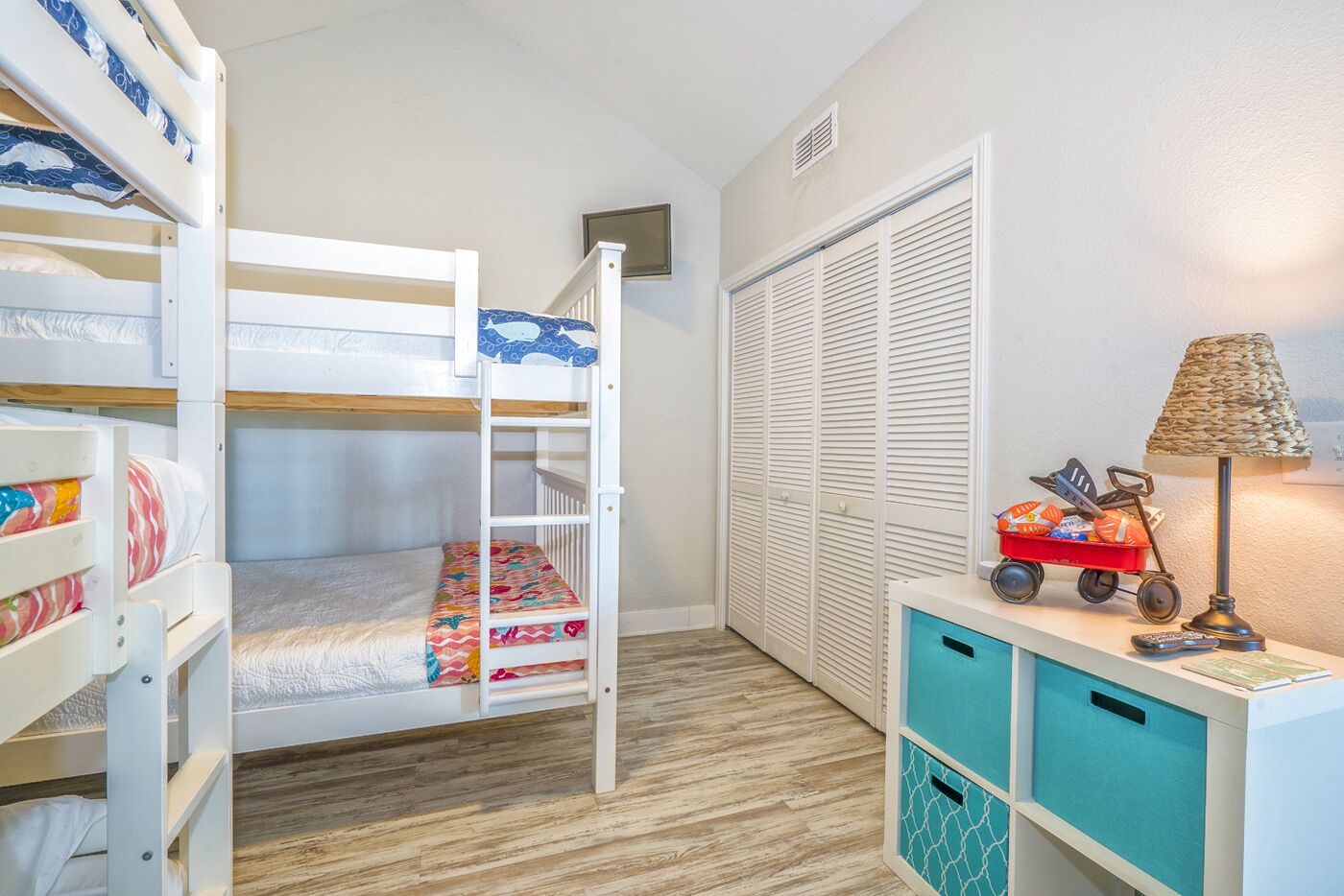 A child's bunk bed with a lower bunk, a toy car, and a lamp on a desk.