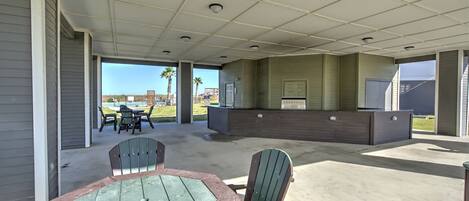 Un espace extérieur abrité doté d’un sol en béton, de deux fauteuils Adirondack, d’une petite table et d’un comptoir d’accueil.