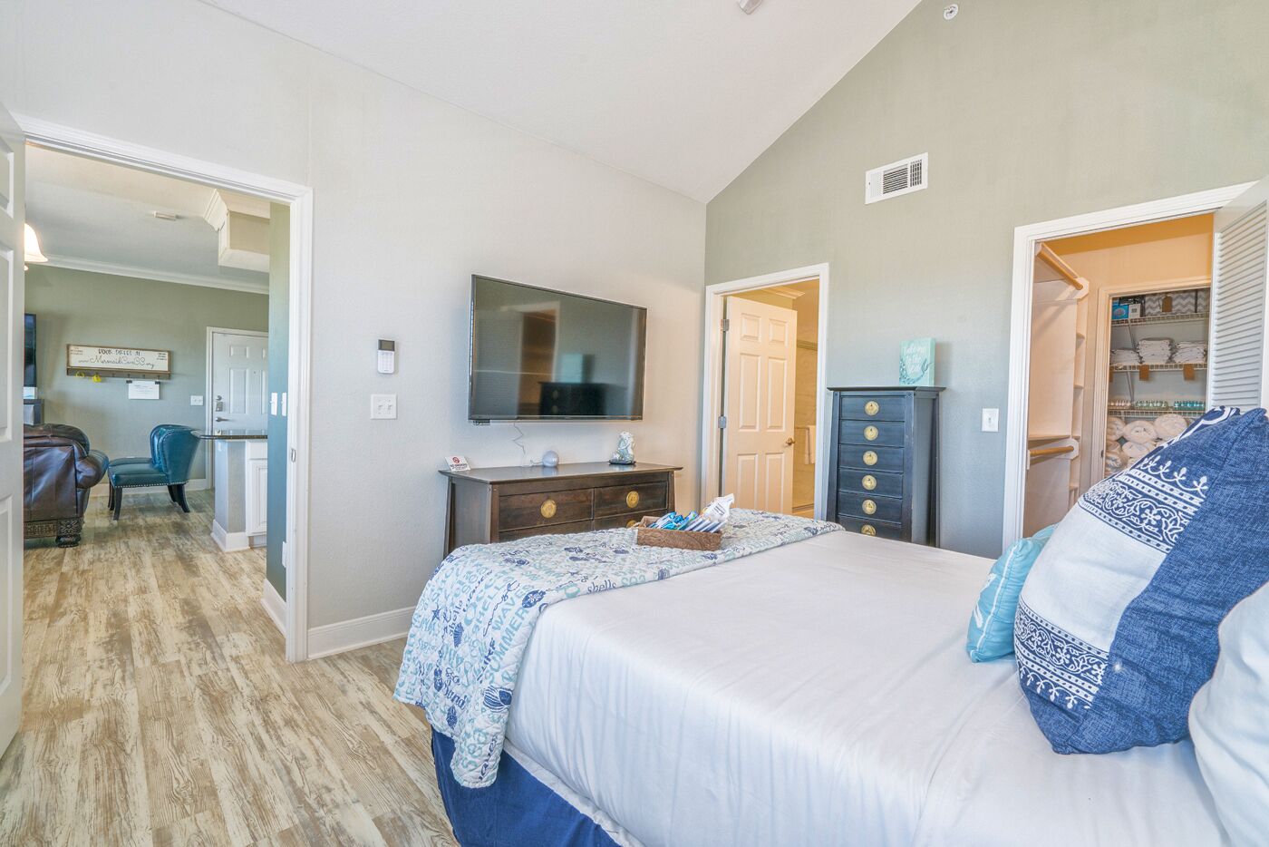A bedroom with a bed, a dresser, a television, and a closet.