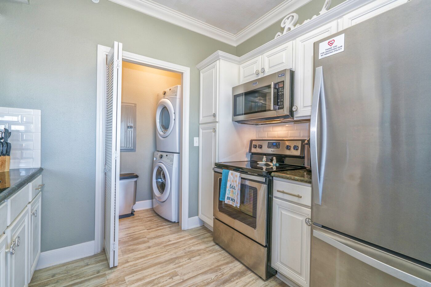 A compact kitchen with a stainless steel refrigerator, a microwave, an oven, and a washing machine.