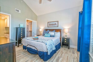 A bedroom with a bed, bedside tables, a dresser, a closet, and a ceiling fan.