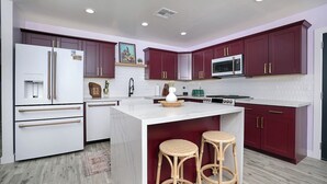 A modern kitchen with a central island, two bar stools, a microwave, and a refrigerator. - Awesome Downtown Gilbert location | Pets welcome (Gilbert)