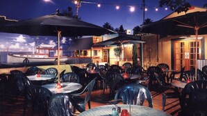 An outdoor dining area with tables and chairs, umbrellas, and string lights. - Awesome Downtown Gilbert location | Pets welcome (Gilbert)