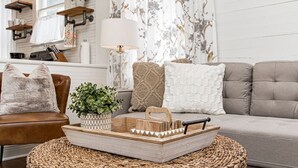 Ein Wohnzimmer mit einem braunen Ledersofa, einem gewebten Couchtisch und einem Holznachttisch mit einer Pflanze.