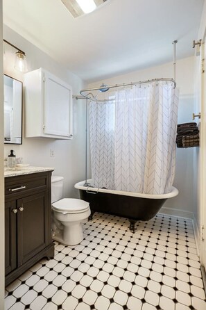 A bathroom with a white toilet, a black bathtub, and a shower curtain with a chevron pattern.