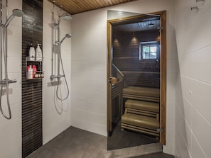 Ein modernes Badezimmer mit Dusche, einer Glastür zu einer Treppe und Pflegeprodukten auf einem Regal.