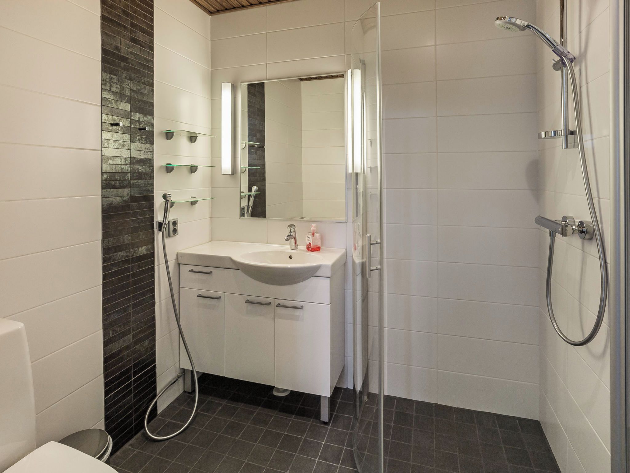 Een moderne badkamer met een wit wastafelmeubel, spiegel en douche.