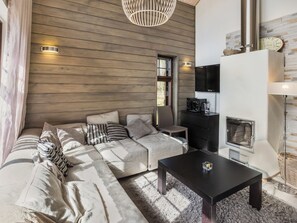 Een moderne woonkamer met een bank, een salontafel, een open haard en een televisie.