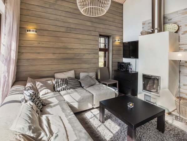 A modern living room with a sofa, a coffee table, a fireplace, and a television.