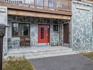A building with a stone facade, a red door, and a wooden deck. - Karhunkieppi 11a by Interhome (Kittilä)