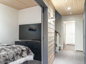 Ein modernes Schlafzimmer mit einem Bett, einem Flachbildfernseher und einem Einbauschrank.