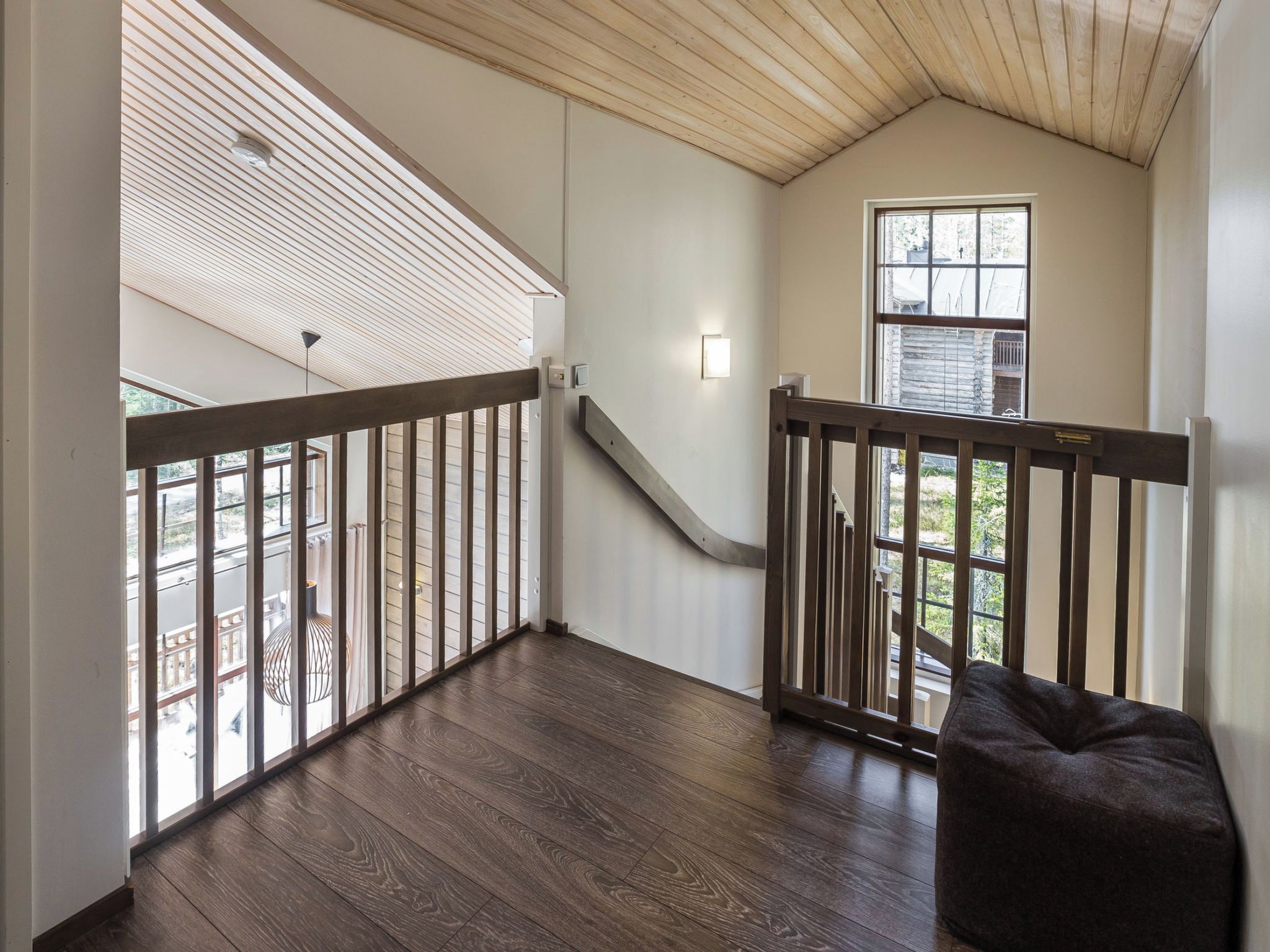 Un balcón amplio con baranda de madera, una escalera que sube a un nivel superior y vistas al exterior.