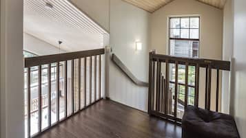 Un balcón amplio con baranda de madera, una escalera que sube a un nivel superior y vistas al exterior.