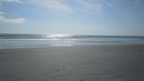 A beach with a wide sandy shore and gentle waves. - Book your Sea Trail getaway in this ground floor, pet friendly condo (Sunset Beach)