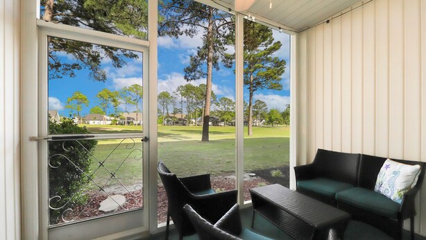 A covered outdoor seating area with a view of a golf course. - Book your Sea Trail getaway in this ground floor, pet friendly condo (Sunset Beach)