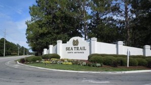 A sign for Sea Trail North Entrance with a white background and a logo. - Book your Sea Trail getaway in this ground floor, pet friendly condo (Sunset Beach)