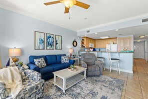 A living room with a blue sofa, a coffee table, and a ceiling fan.