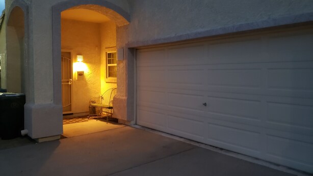 A garage entrance with a white door, a small window, and a light fixture above the door. - Centrally Located Mesa Studio (Mesa)