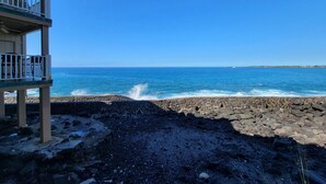 Um edifício com varanda voltada para uma costa rochosa e o oceano.