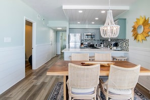 A modern kitchen with a central island, white cabinetry, and a decorative sunburst mirror.